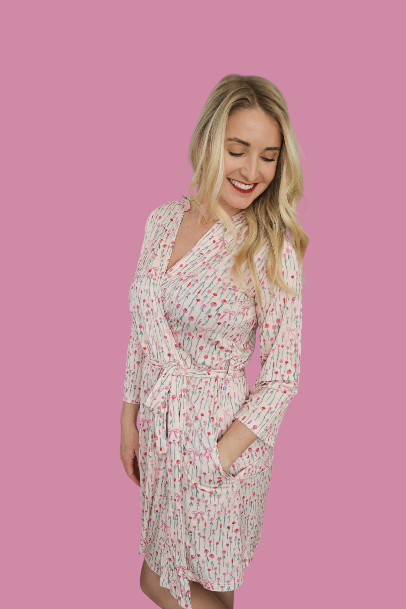 Woman in Blooms & Bows Women’s Dream Robe with floral print on pink background, smiling and showcasing a comfortable fit.