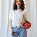 Cherry Cute Button Down featuring a cherry embroidered scallop hem and short puff sleeves, styled with a red bag.