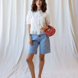 Model wearing Cherry Cute Button Down with puff sleeves, showcasing cherry embroidery and a stylish red bag.