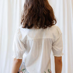 Back view of a woman wearing the Cherry Cute Button Down with cherry embroidered scallop hem.