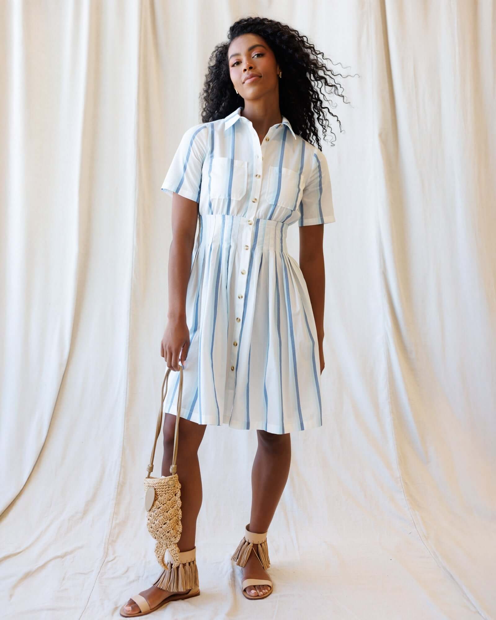 Model wearing a Seaside Stripe Dress with collared neckline, button-down front, and relaxed pleated skirt.