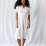 Model wearing a Swiss Dot Scallop Dress featuring pintuck details and short puff sleeves.