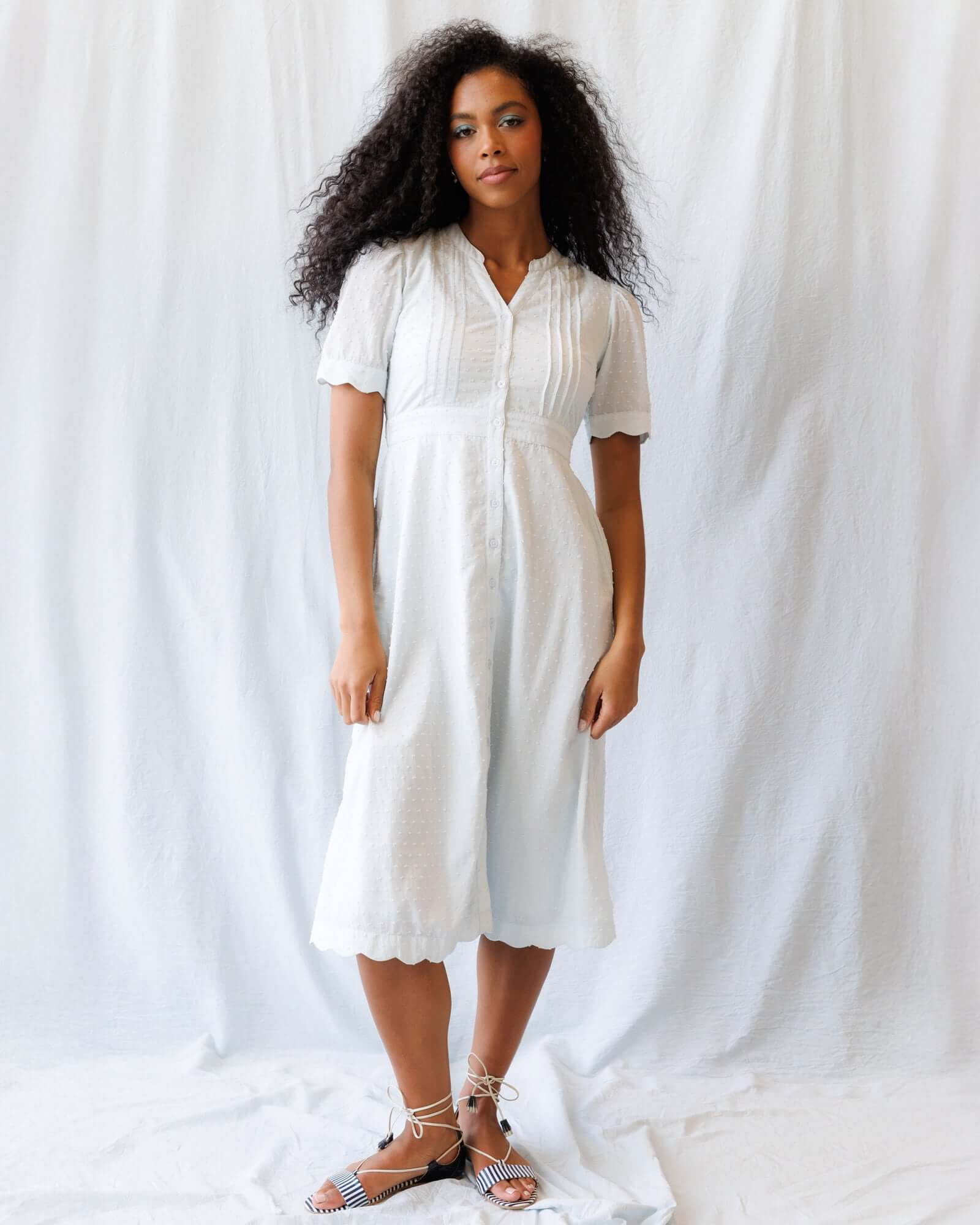 Model wearing a Swiss Dot Scallop Dress featuring pintuck details and short puff sleeves.