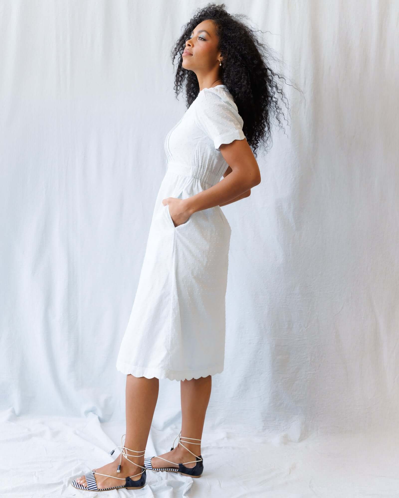 Model wearing the Swiss Dot Scallop Dress, showcasing its short puff sleeves, pintuck bodice, and A-line midi design.