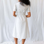 Back view of a woman wearing a Swiss Dot Scallop Dress with puff sleeves and a midi length skirt, perfect for nursing.
