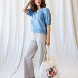 Model wearing Portside Chambray Popover with short puff sleeves, styled with casual pants and a tote bag.
