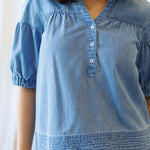 Model wearing Portside Chambray Popover featuring short puff sleeves and dark wash chambray fabric.