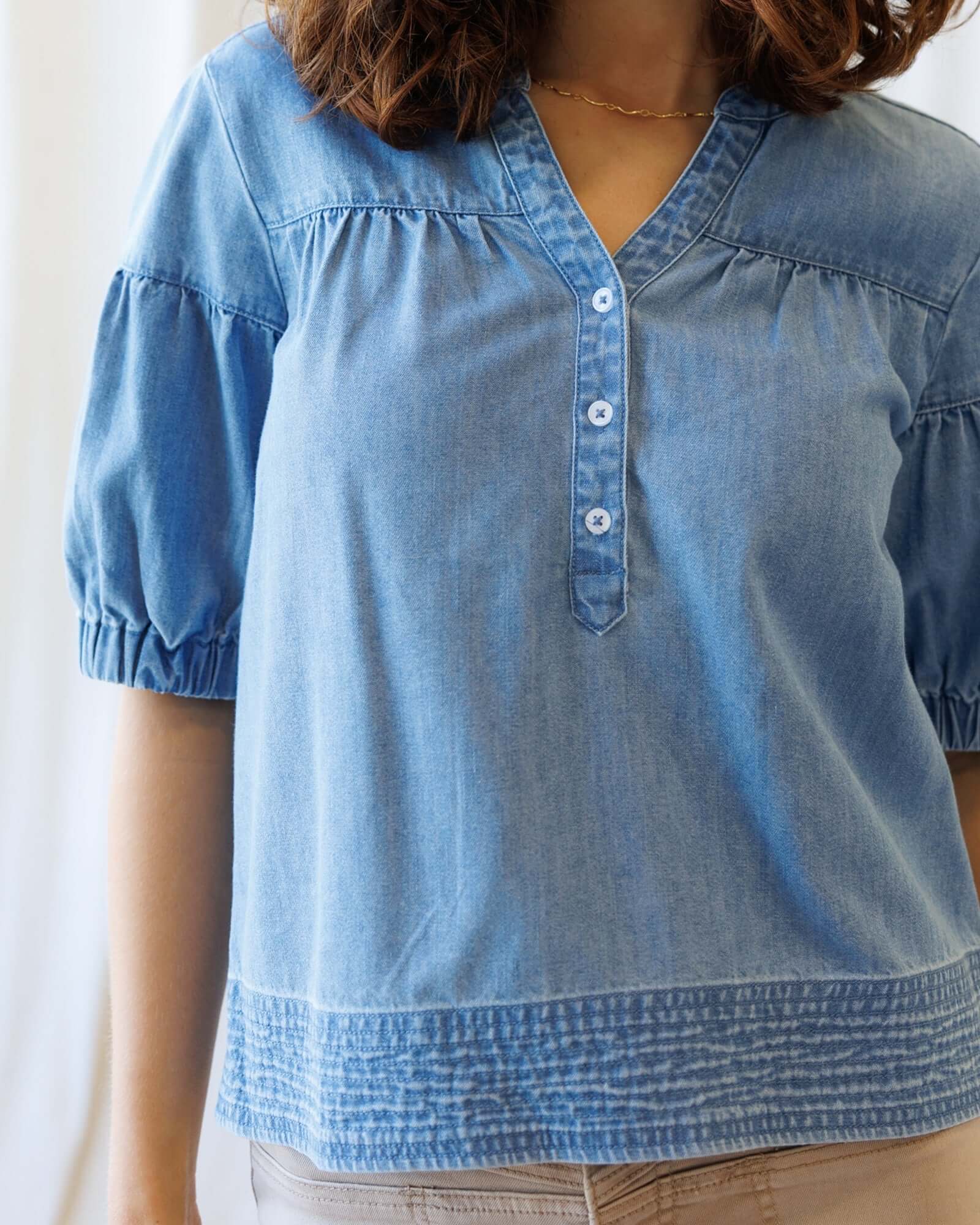 Model wearing Portside Chambray Popover featuring short puff sleeves and dark wash chambray fabric.