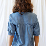 Back view of the Portside Chambray Popover showing short puff sleeves and relaxed fit, perfect for summer outings.
