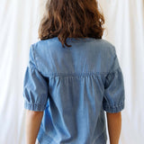 Back view of the Portside Chambray Popover showing short puff sleeves and relaxed fit, perfect for summer outings.
