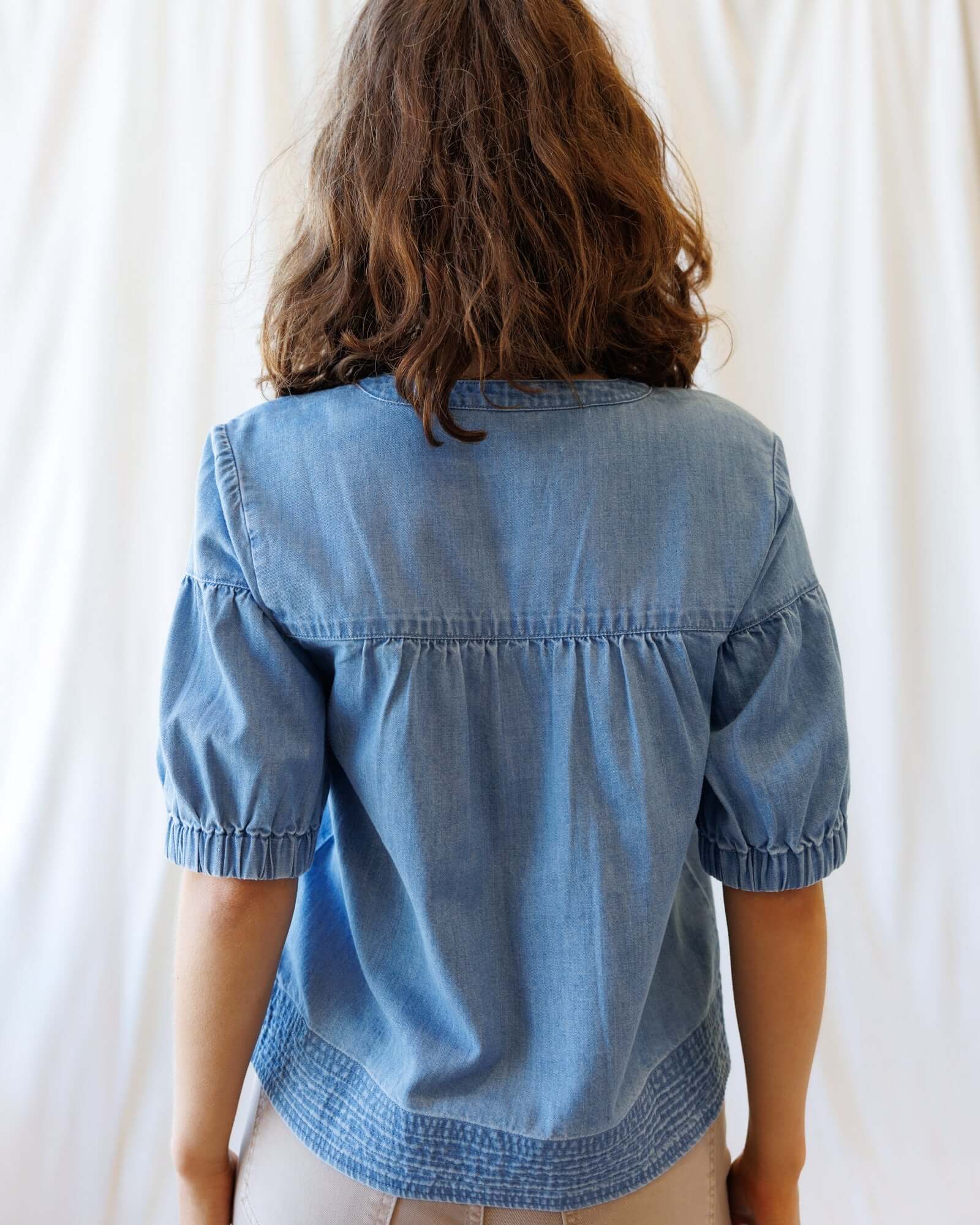 Back view of the Portside Chambray Popover showing short puff sleeves and relaxed fit, perfect for summer outings.