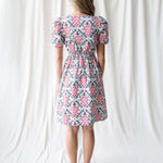Back view of a model wearing a floral Capri Dress with puff sleeves, perfect for nursing friendly style with Milk & Baby.