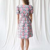 Back view of a model wearing a floral Capri Dress with puff sleeves, perfect for nursing friendly style with Milk & Baby.