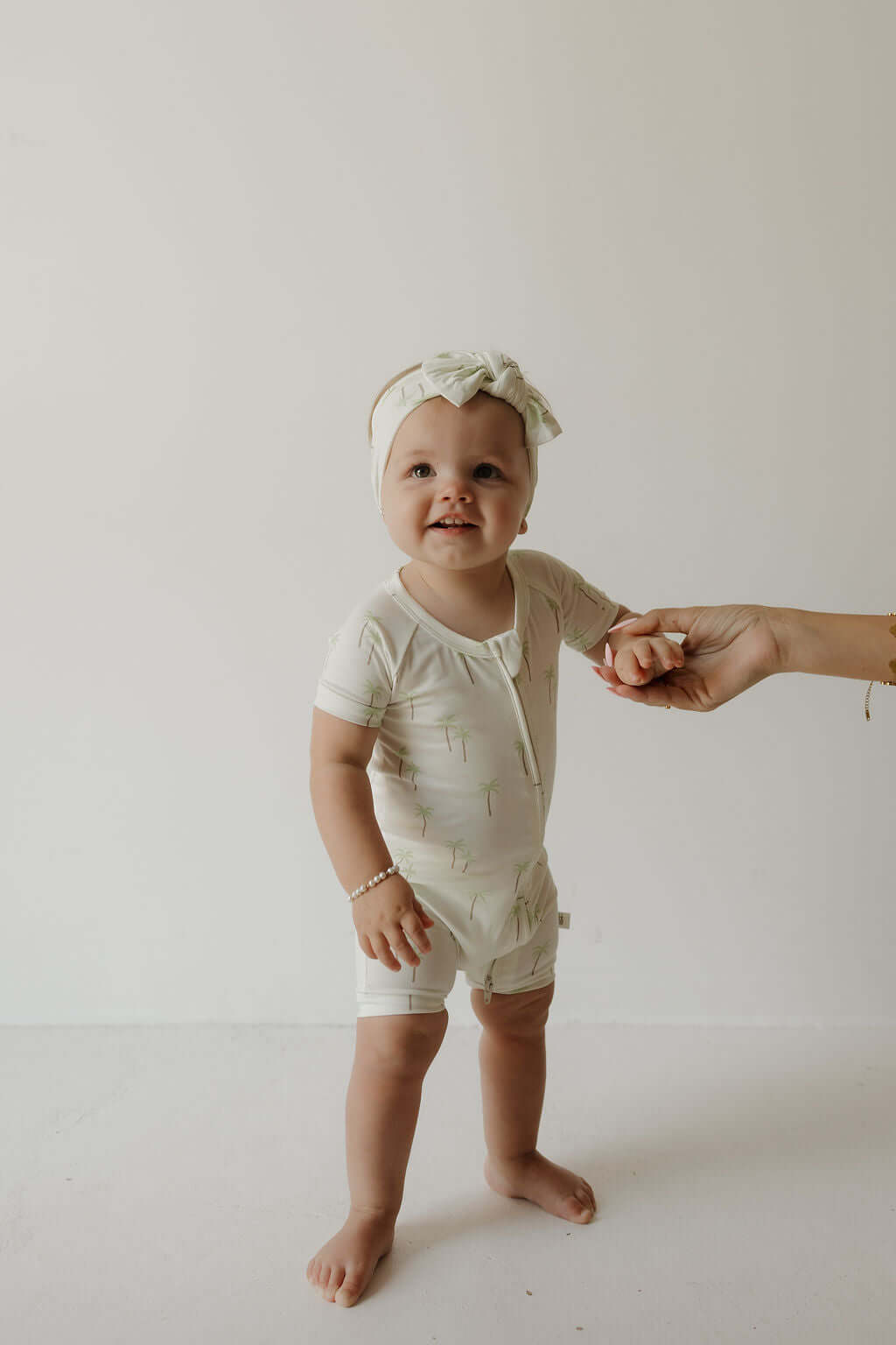 Palm | Bamboo Head Wrap | Milk & Baby | Made from silky-soft bamboo material, this adjustable head wrap features a sweet bow for added style. Perfect for babies and toddlers!One size fits most Print: Palm (a palm tree print on cream background) Material: