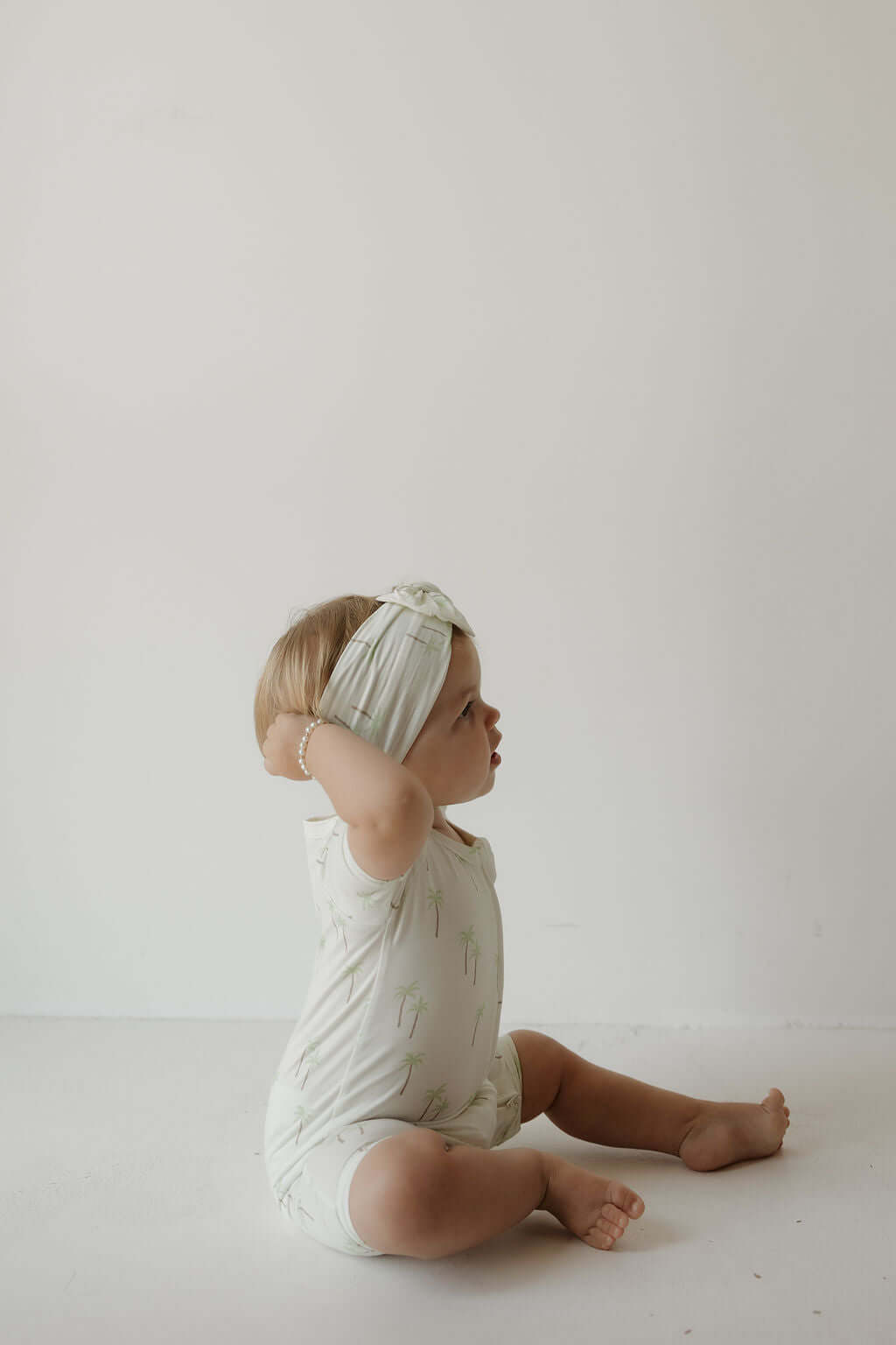Palm | Bamboo Head Wrap | Milk & Baby | Made from silky-soft bamboo material, this adjustable head wrap features a sweet bow for added style. Perfect for babies and toddlers!One size fits most Print: Palm (a palm tree print on cream background) Material: