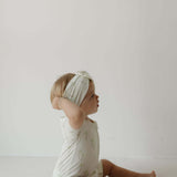 Palm | Bamboo Head Wrap | Milk & Baby | Made from silky-soft bamboo material, this adjustable head wrap features a sweet bow for added style. Perfect for babies and toddlers!One size fits most Print: Palm (a palm tree print on cream background) Material: