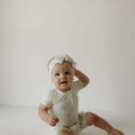 Palm | Bamboo Head Wrap | Milk & Baby | Made from silky-soft bamboo material, this adjustable head wrap features a sweet bow for added style. Perfect for babies and toddlers!One size fits most Print: Palm (a palm tree print on cream background) Material: