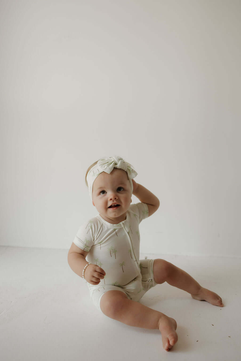 Palm | Bamboo Head Wrap | Milk & Baby | Made from silky-soft bamboo material, this adjustable head wrap features a sweet bow for added style. Perfect for babies and toddlers!One size fits most Print: Palm (a palm tree print on cream background) Material: