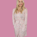 Woman wearing the Blooms & Bows Women’s Dream Robe with floral design, smiling against a pink background.