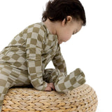 Toddler wearing Sage Check | Zip Romper sitting on a woven pouf, showcasing soft bamboo blend fabric.