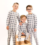 Slate Gingham | Zip Romper. Three kids posing in soft bamboo rompers with checkered pattern on a wooden chair.