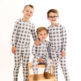 Slate Gingham | Zip Romper. Three kids posing in soft bamboo rompers with checkered pattern on a wooden chair.