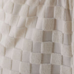 Close-up of textured white fabric with a checkered pattern