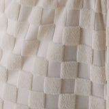 Close-up of textured white fabric with a checkered pattern