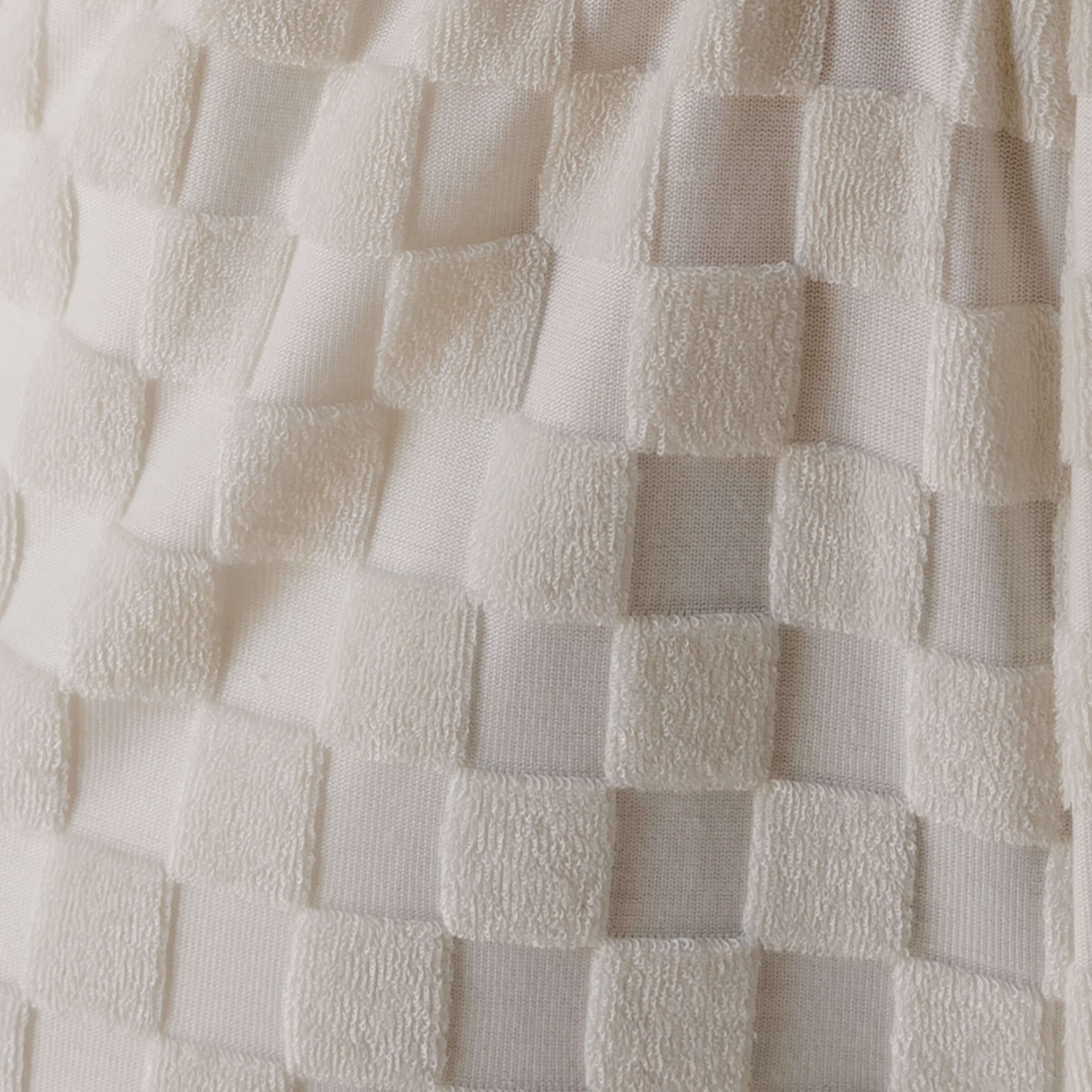 Close-up of textured white fabric with a checkered pattern