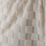 Close-up of textured white fabric with a checkered pattern