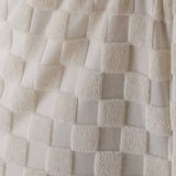 Close-up of textured white fabric with a checkered pattern