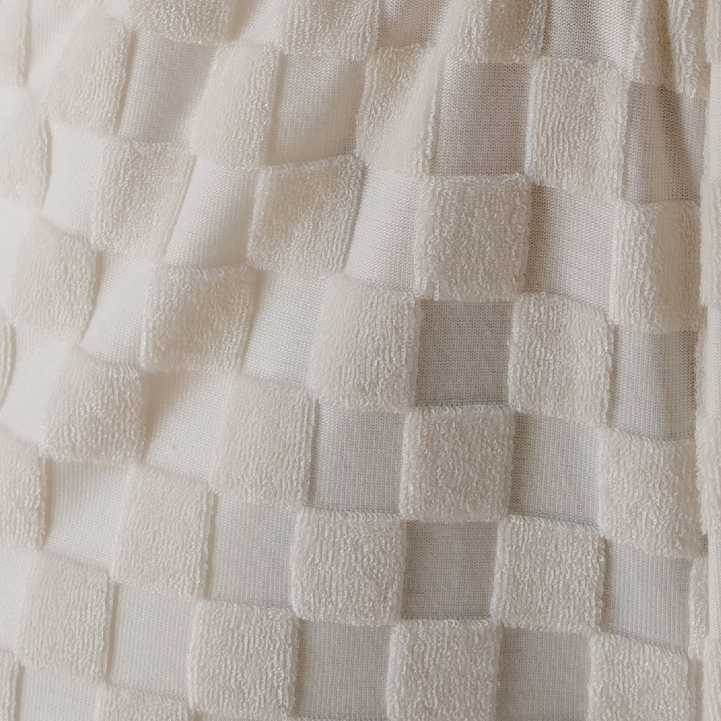 Close-up of textured white fabric with a checkered pattern