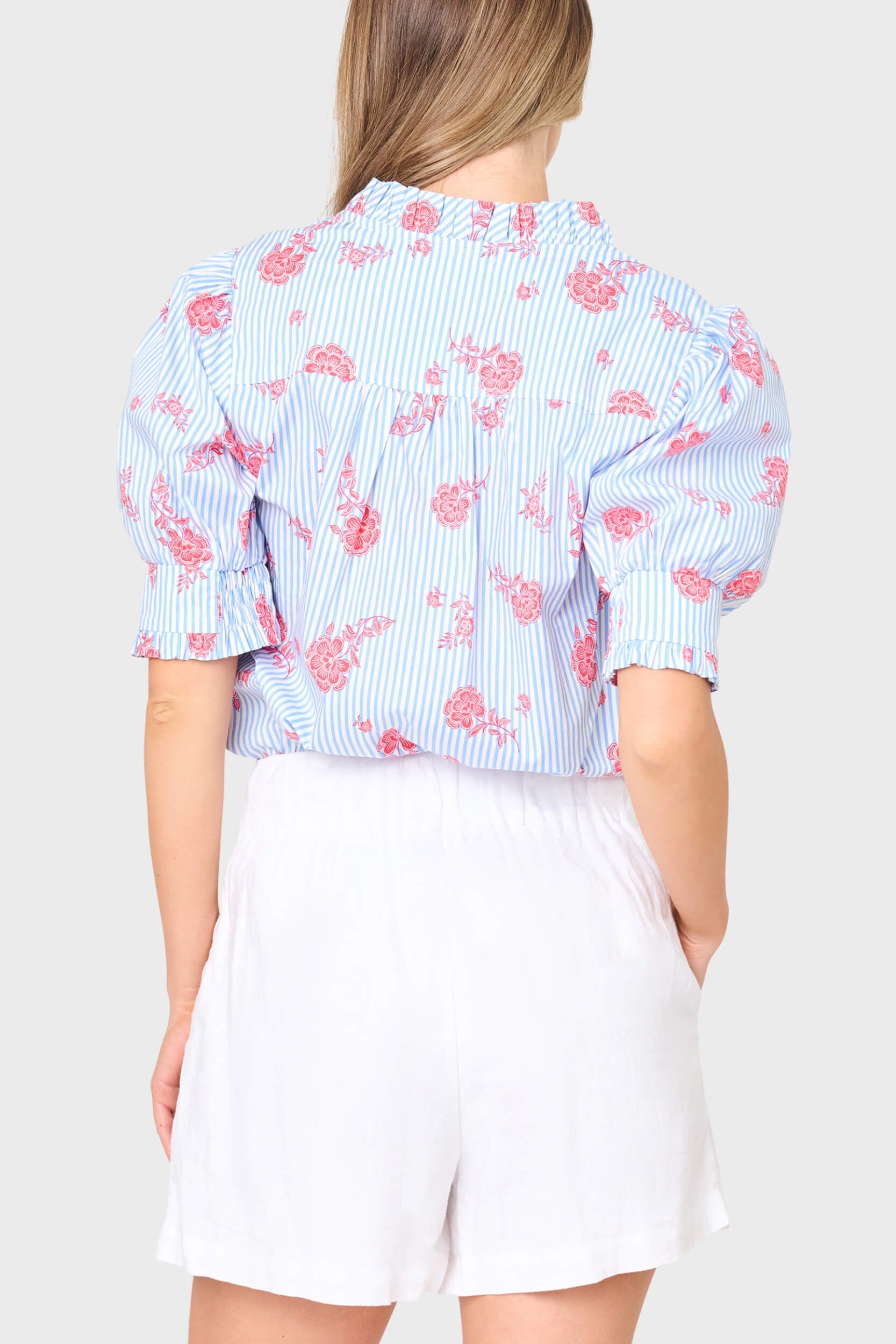 Woman wearing a light blue floral blouse with pink flowers on a white background
