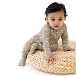 Cute baby in a Sage Floral | Zip Romper sitting on a comfy round basket.