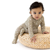 Cute baby in a Sage Floral | Zip Romper sitting on a comfy round basket.