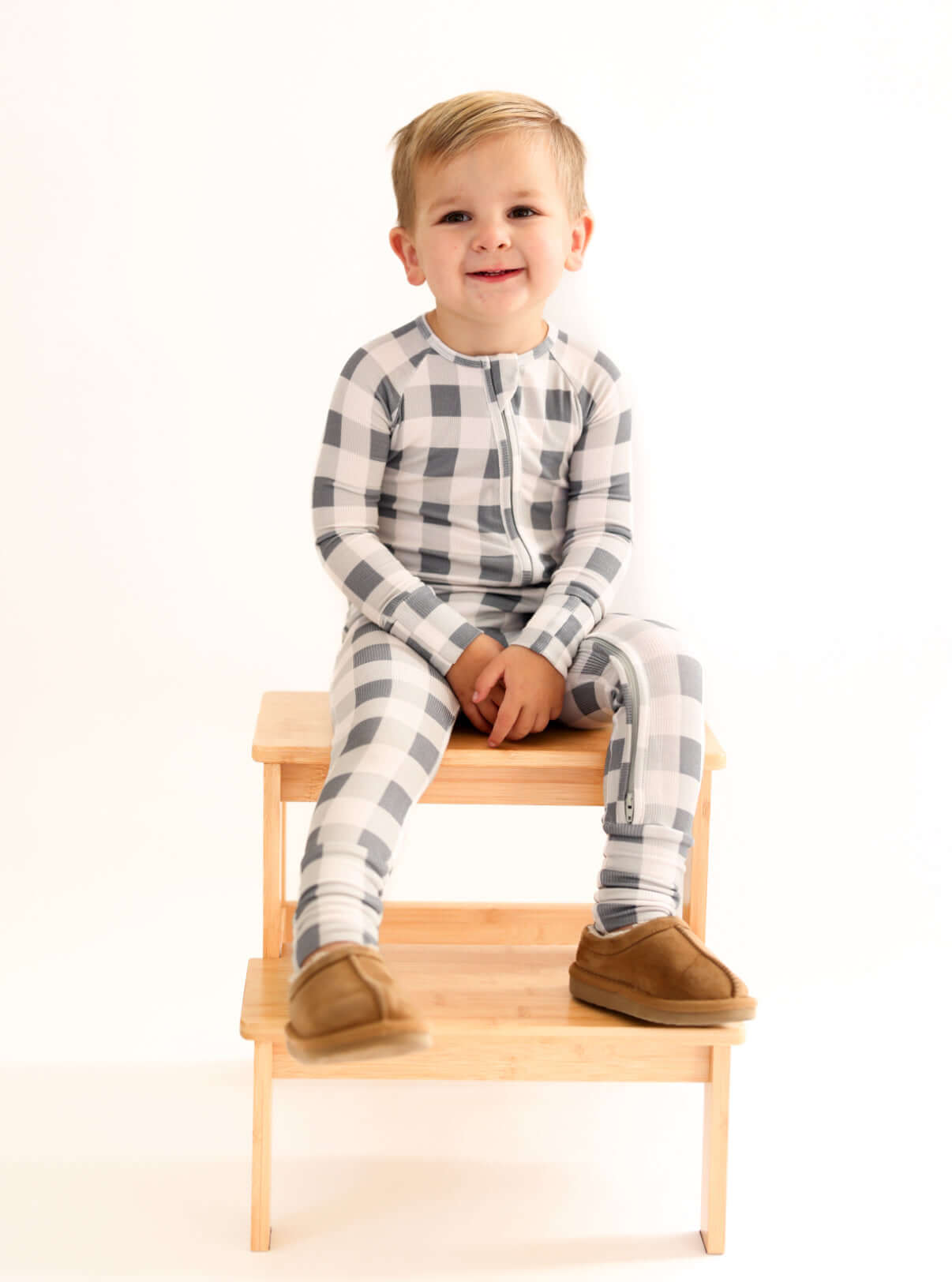 Slate Gingham | Zip Romper on a happy child sitting on a wooden stool, showcasing soft bamboo comfort.