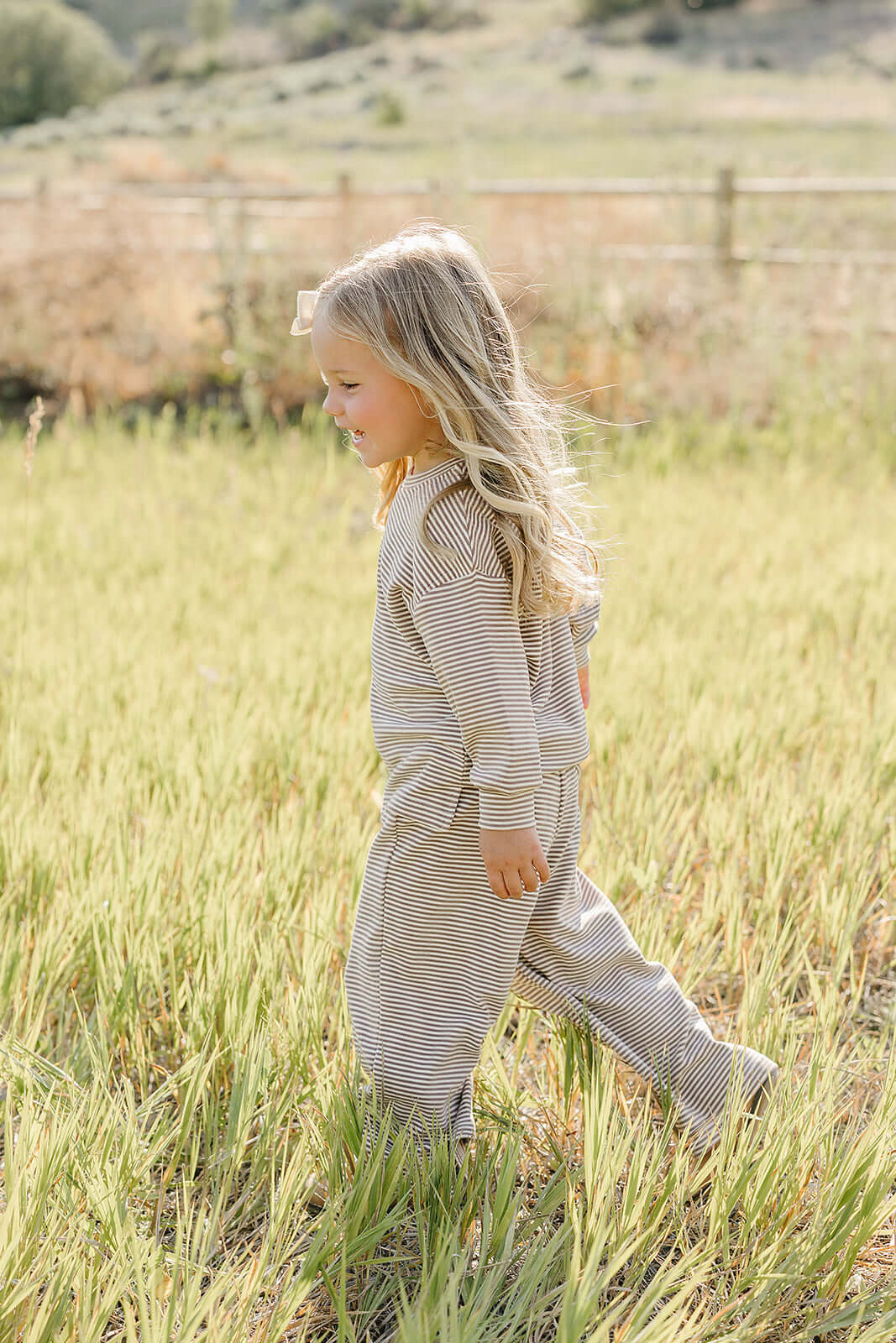 A happy child in a striped loungewear set running through a field, perfect for cozy playtime | Striped Loungewear Set | Babies & Kids.