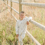 Young boy in Mebie Baby Skier French Terry Set enjoying the outdoors next to a wooden fence.