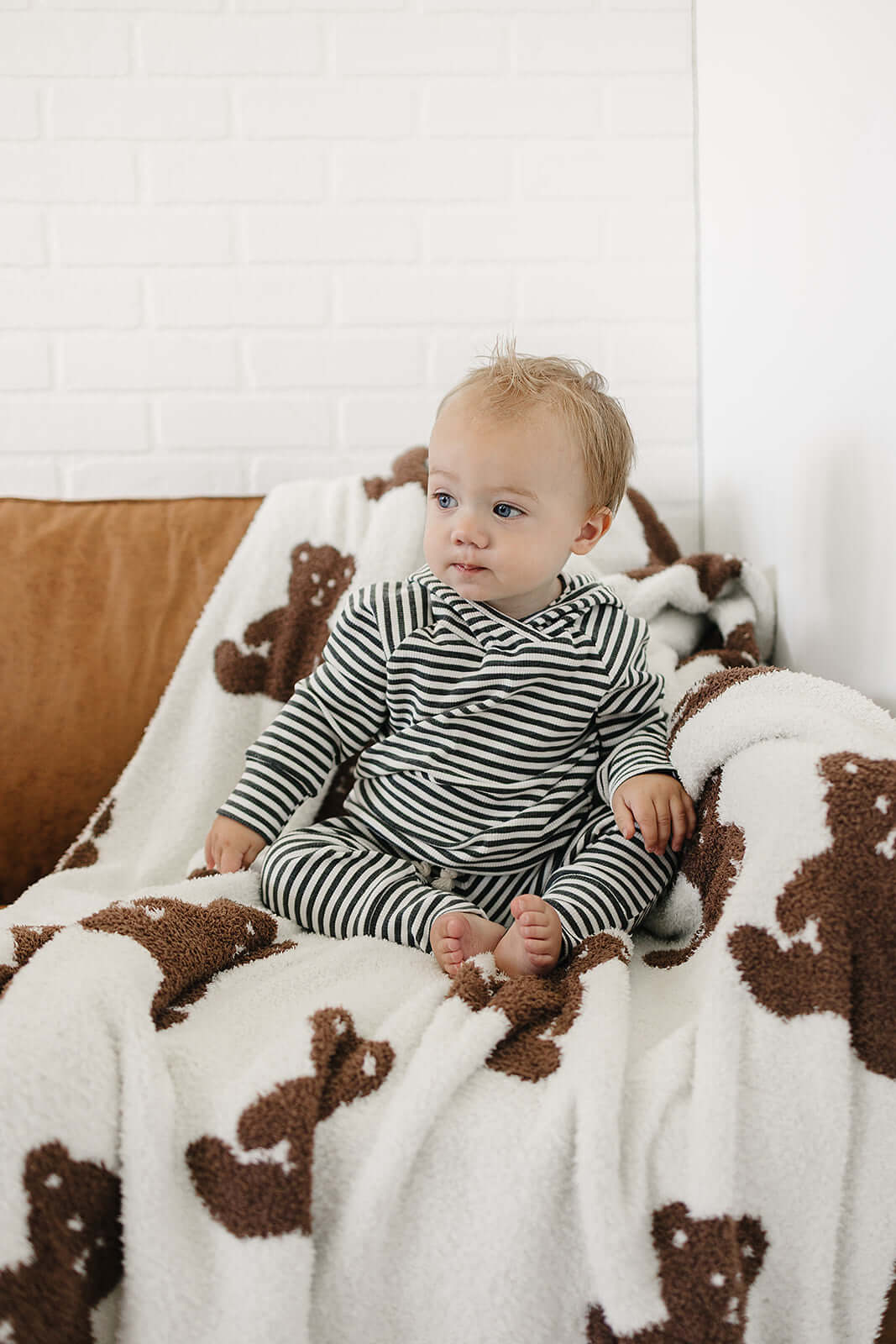 Adorable baby in the Charcoal Stripe Ribbed Hooded Set sitting on a cozy blanket with teddy bears.