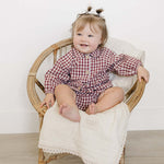 Adorable baby wearing a Red Gingham Peter Pan Collar Bloomer Set, sitting on a chair and smiling