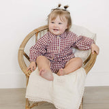 Adorable baby wearing a Red Gingham Peter Pan Collar Bloomer Set, sitting on a chair and smiling