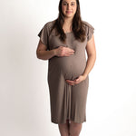 Pregnant woman wearing a Ribbed Cocoa Brown Labor & Delivery Gown, standing and holding her belly.