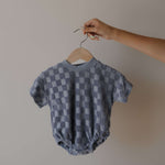 Checkered baby romper on a hanger against a plain background
