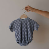 Checkered baby romper on a hanger against a plain background