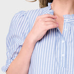 Woman wearing a blue and white striped shirt against a plain background