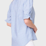 Woman wearing a blue and white striped shirt with rolled-up sleeves on a plain background