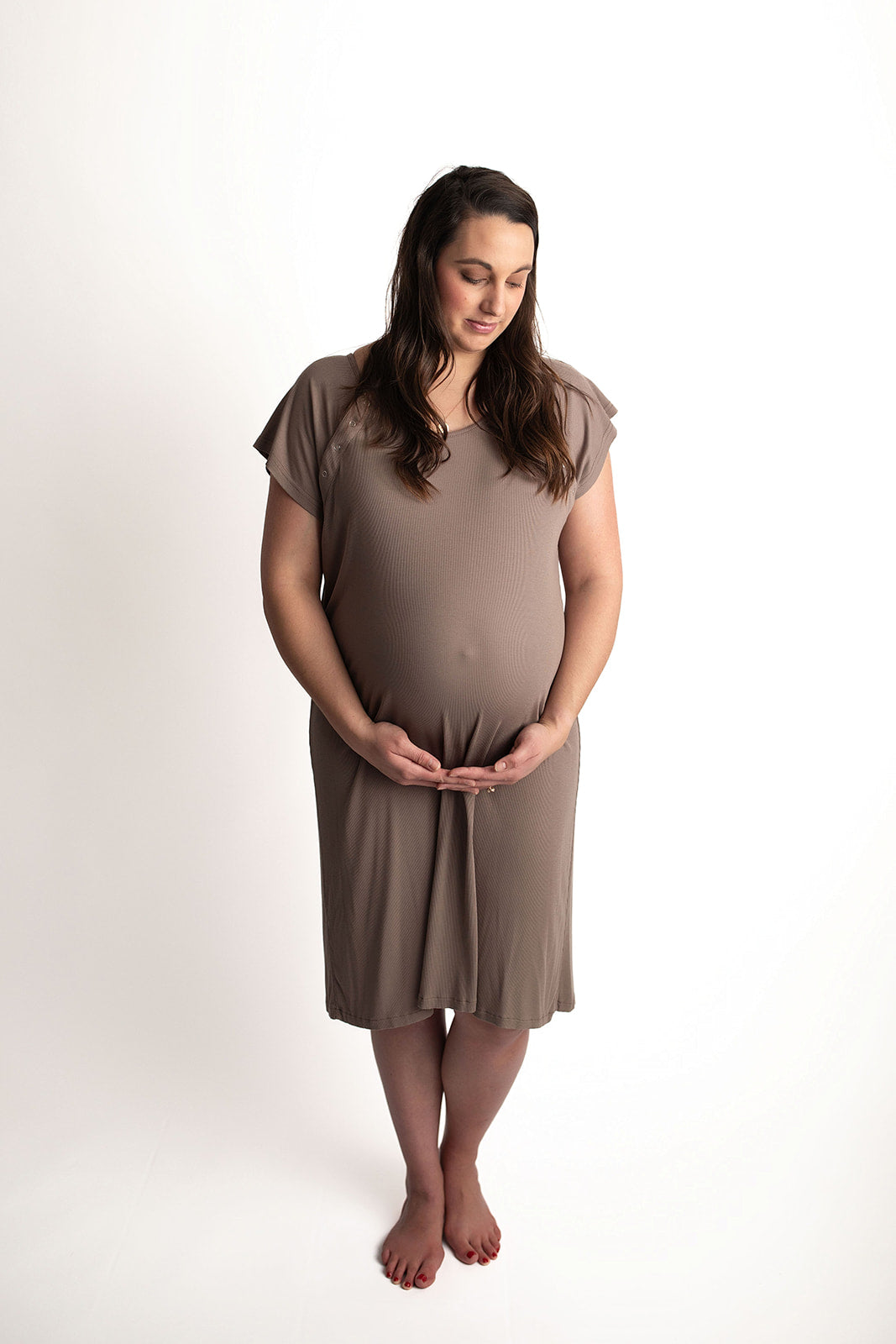 Pregnant woman wearing a Ribbed Cocoa Brown Labor & Delivery Gown, holding her belly.