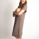 Woman in a ribbed cocoa brown Labor & Delivery Gown holding a newborn baby while standing barefoot.