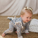 Baby crawling in the Blue Meadow Ruffle French Terry Set, showcasing floral print and ruffles.