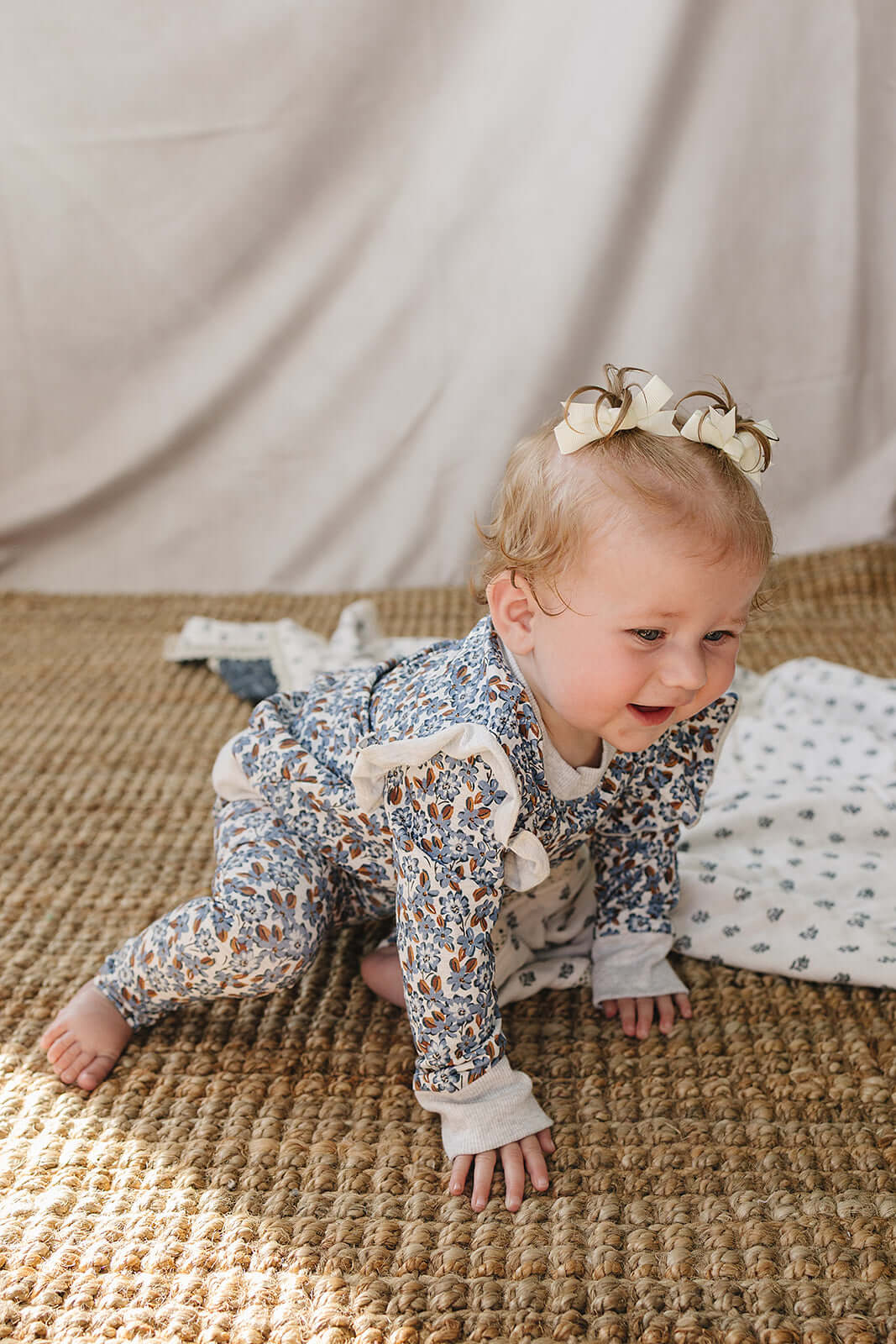 Baby crawling in the Blue Meadow Ruffle French Terry Set, showcasing floral print and ruffles.